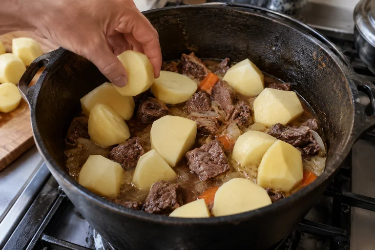 Крупные куски картофеля выкладывают поверх мяса в казане